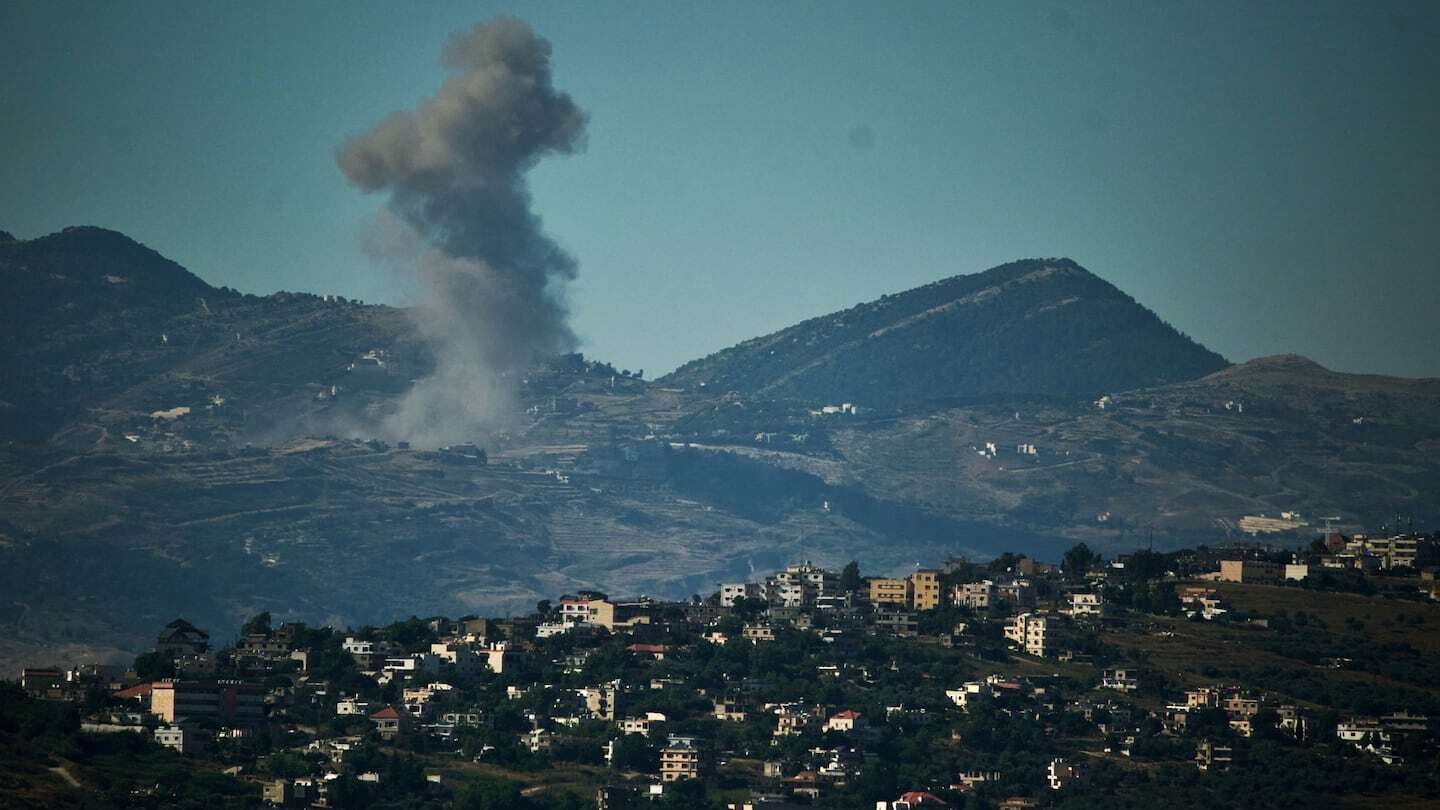 Nubes de humo elevándose sobre montañas y un pueblo en el fondo