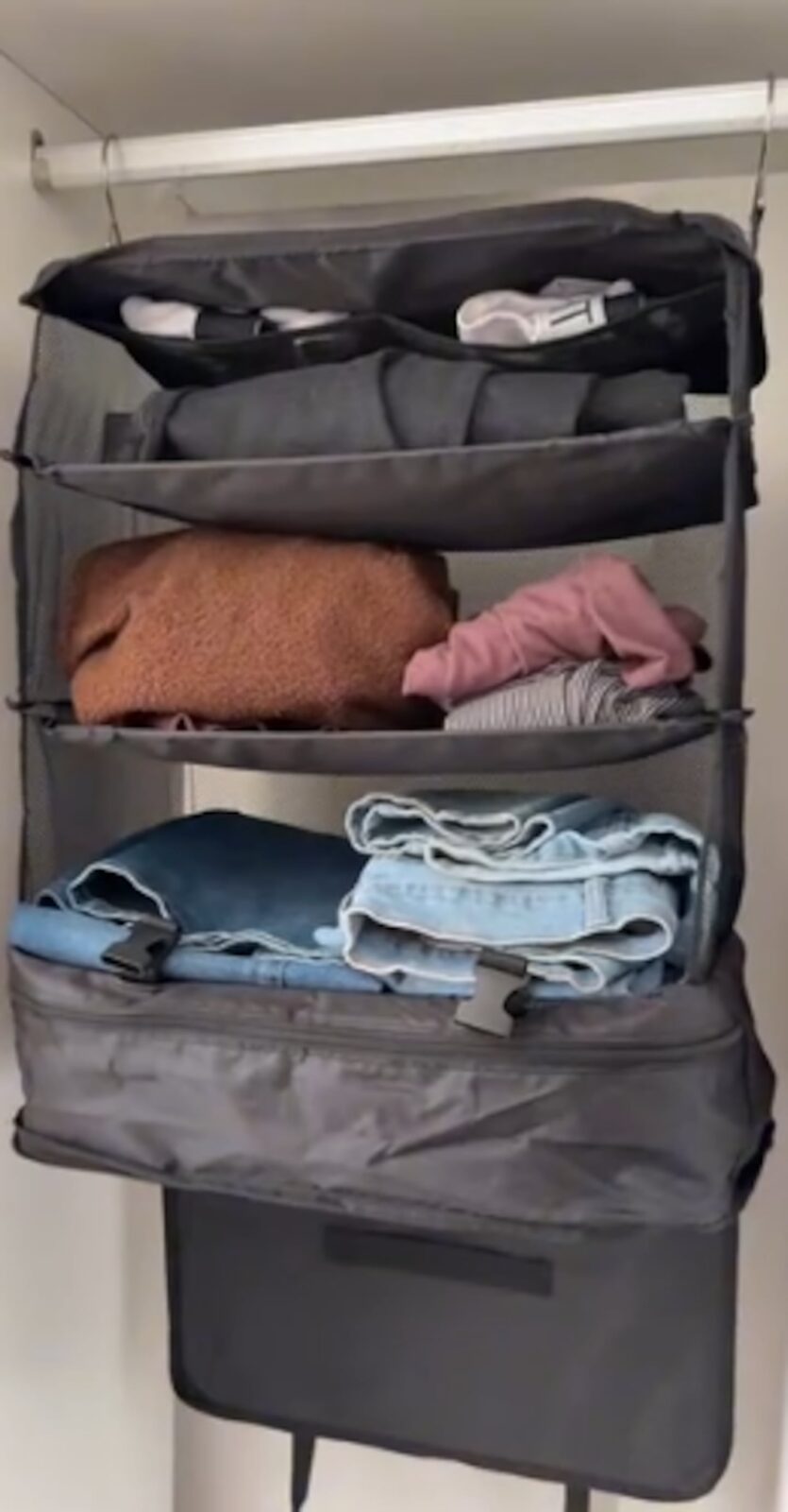 Organizador de equipaje con ropa doblada en estantes