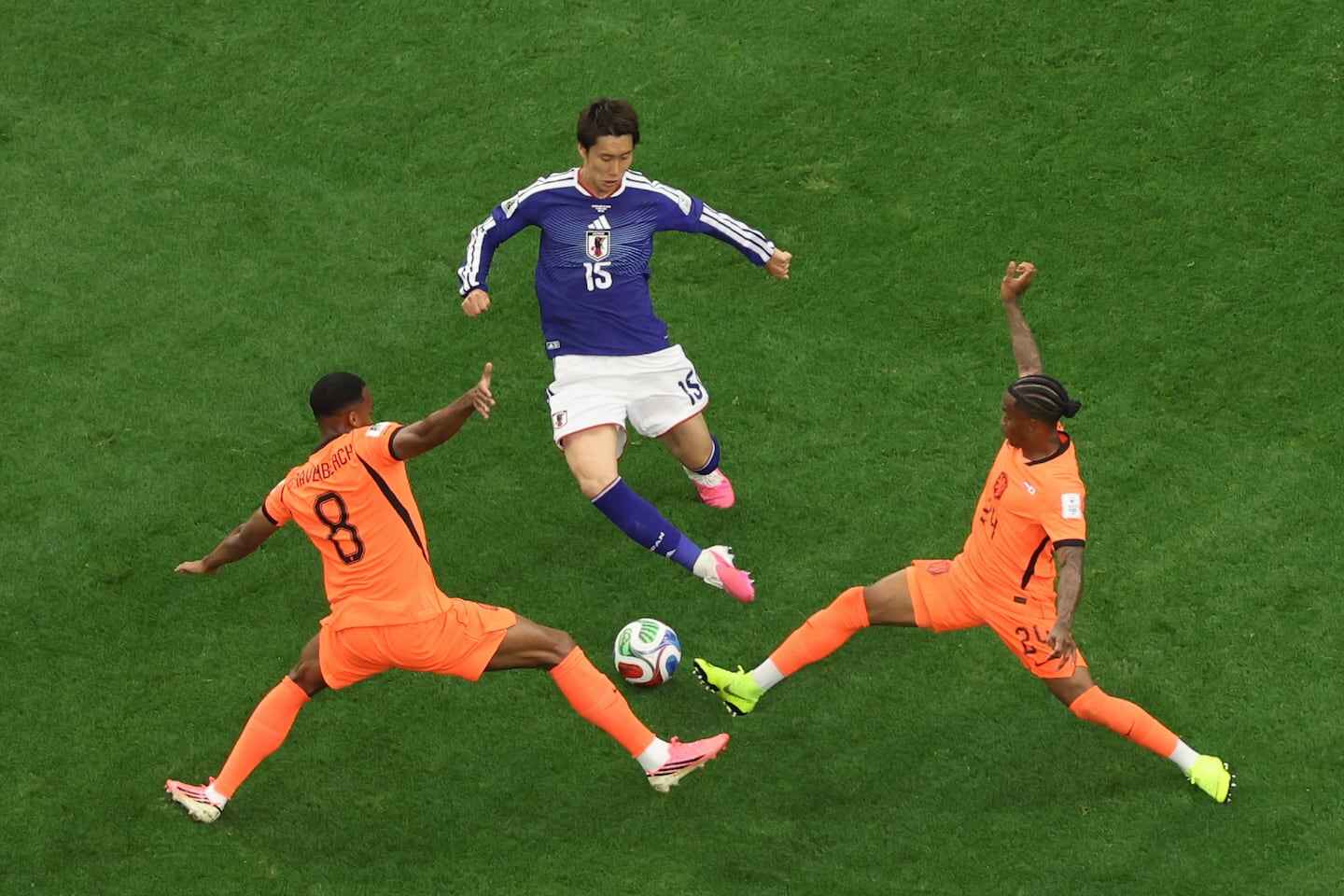 Jugador japonés esquivando a dos defensores de Túnez durante un partido de fútbol
