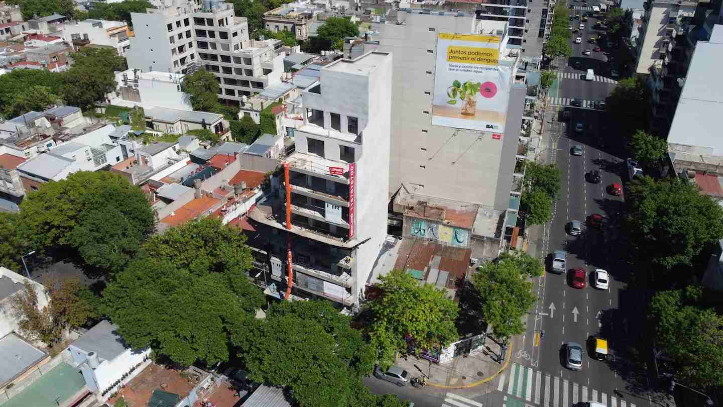 Vista aérea de un edificio en construcción en Buenos Aires, rodeado de árboles y otras edificaciones