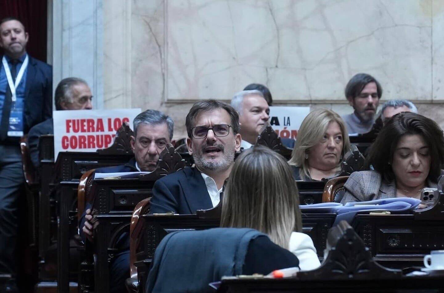 Debate en el Congreso con legisladores y carteles de protesta