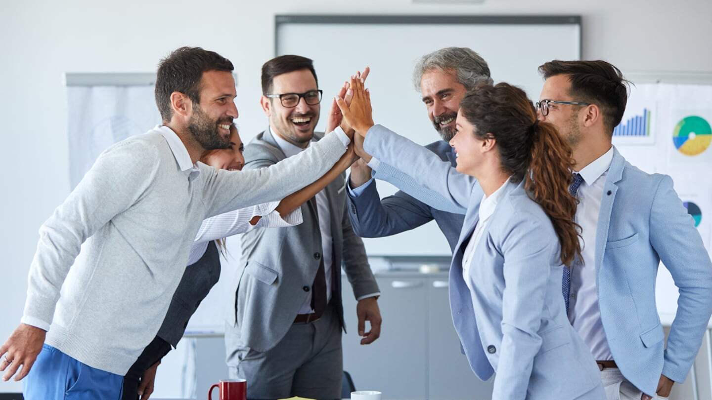 Grupo de profesionales celebrando un logro en una reunión de trabajo