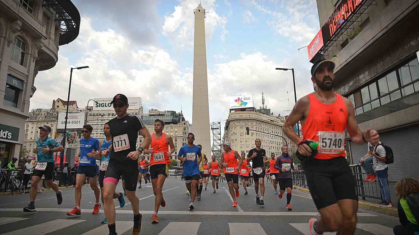 Corredores participan en una maratón en una ciudad con un obelisco al fondo