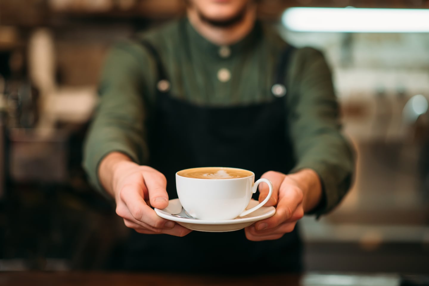 Barista sosteniendo una taza de café en un platillo