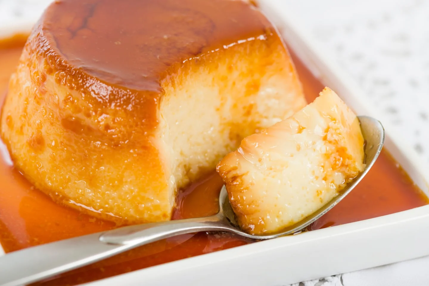 Flan casero suave con caramelo en un plato blanco