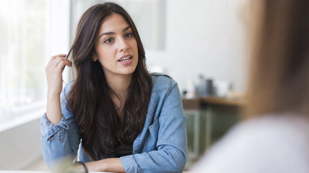 Persona tocándose el pelo durante una conversación