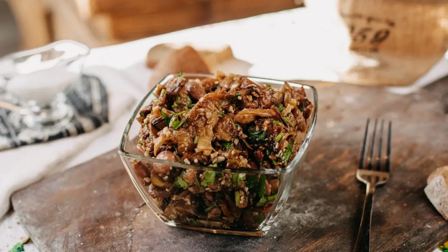 Ensalada de carne desmenuzada en un bol de vidrio sobre una mesa rústica