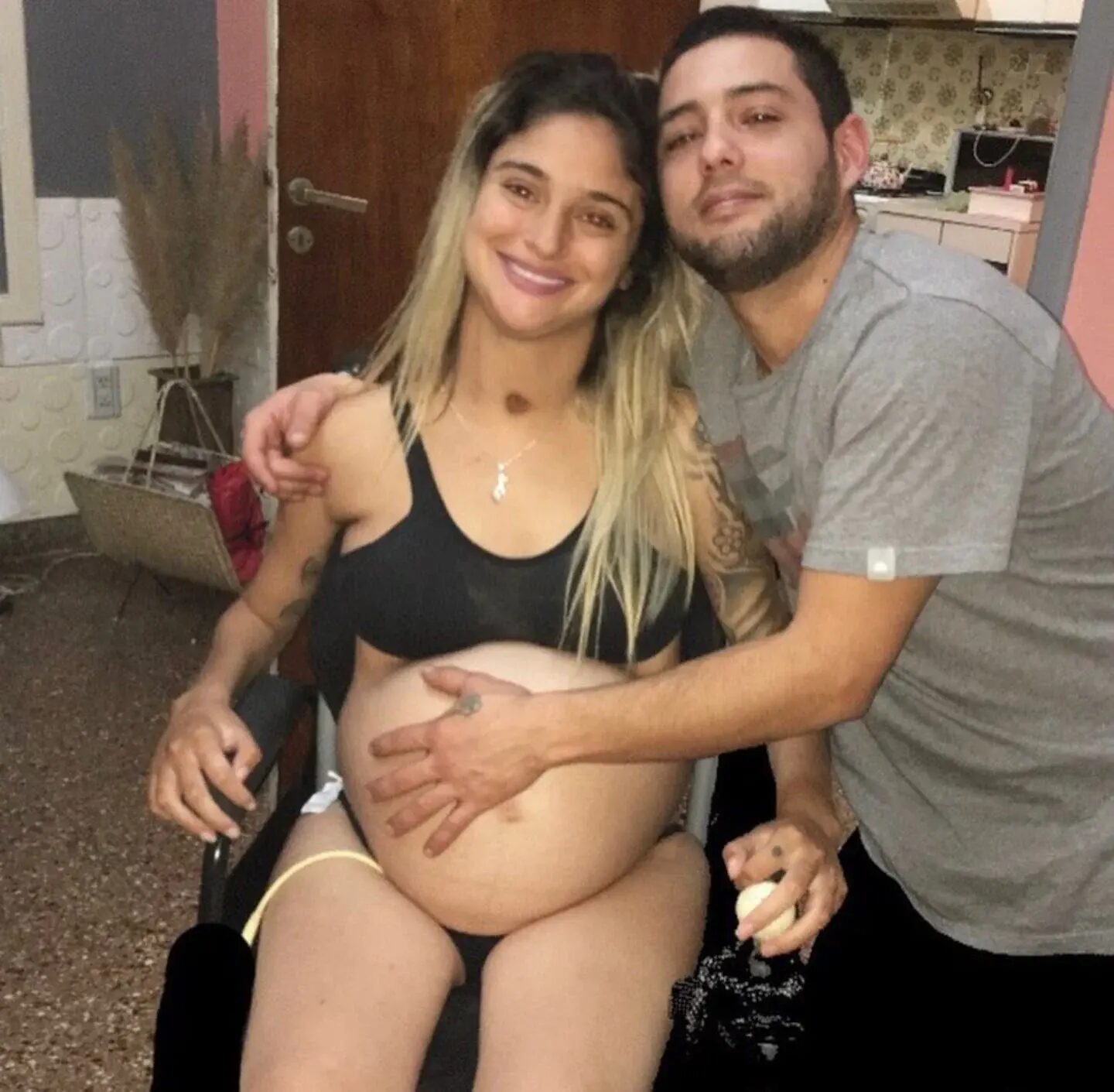 Giselle Agostino embarazada posando con su pareja en una silla de ruedas