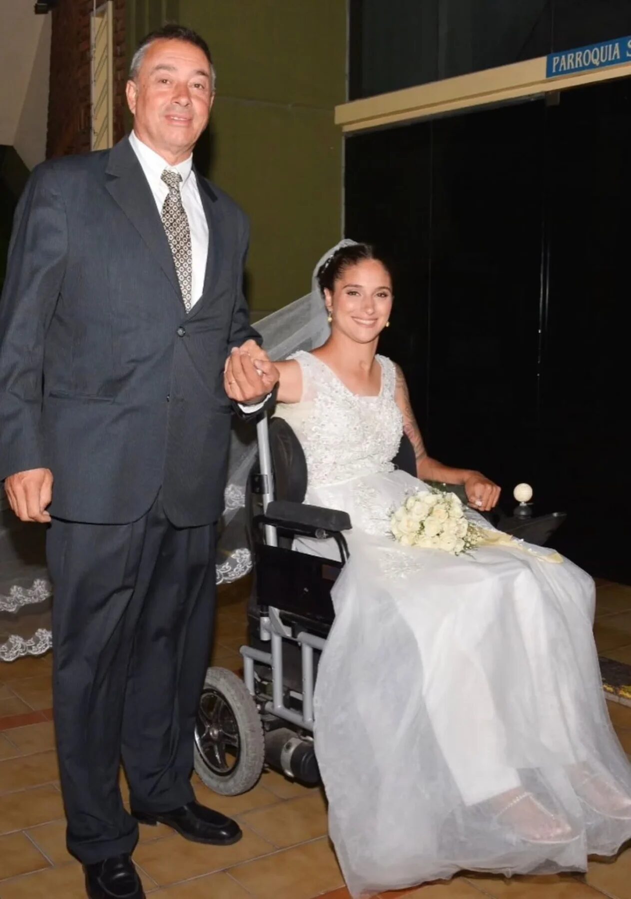 Giselle Agostino en su boda, sonriente y en silla de ruedas, acompañada por su padre