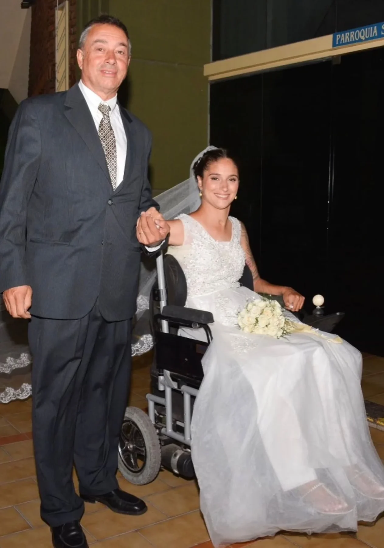 Giselle Agostino en su boda, sonriente y en silla de ruedas, acompañada por su padre