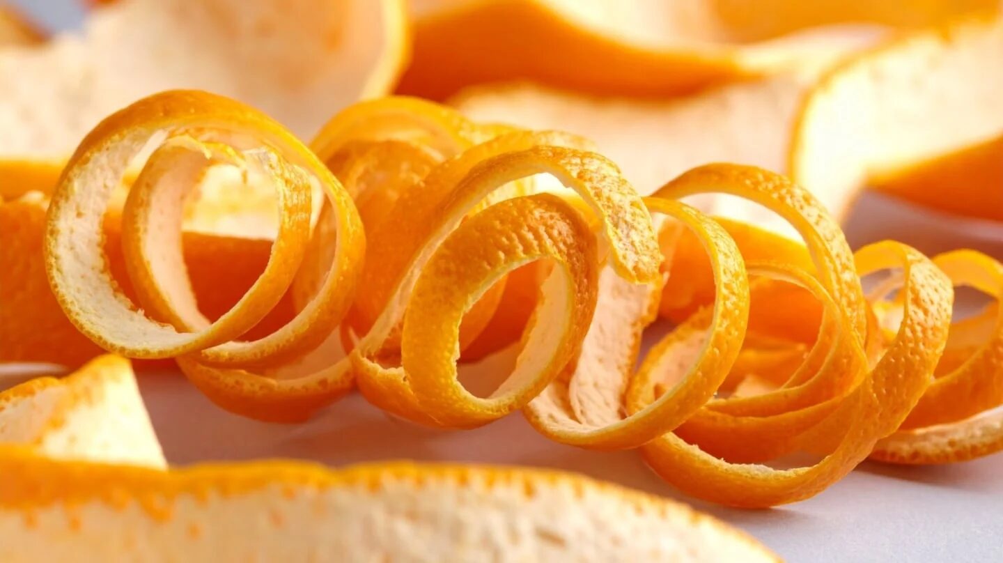Cáscaras de naranja en espiral sobre una superficie clara