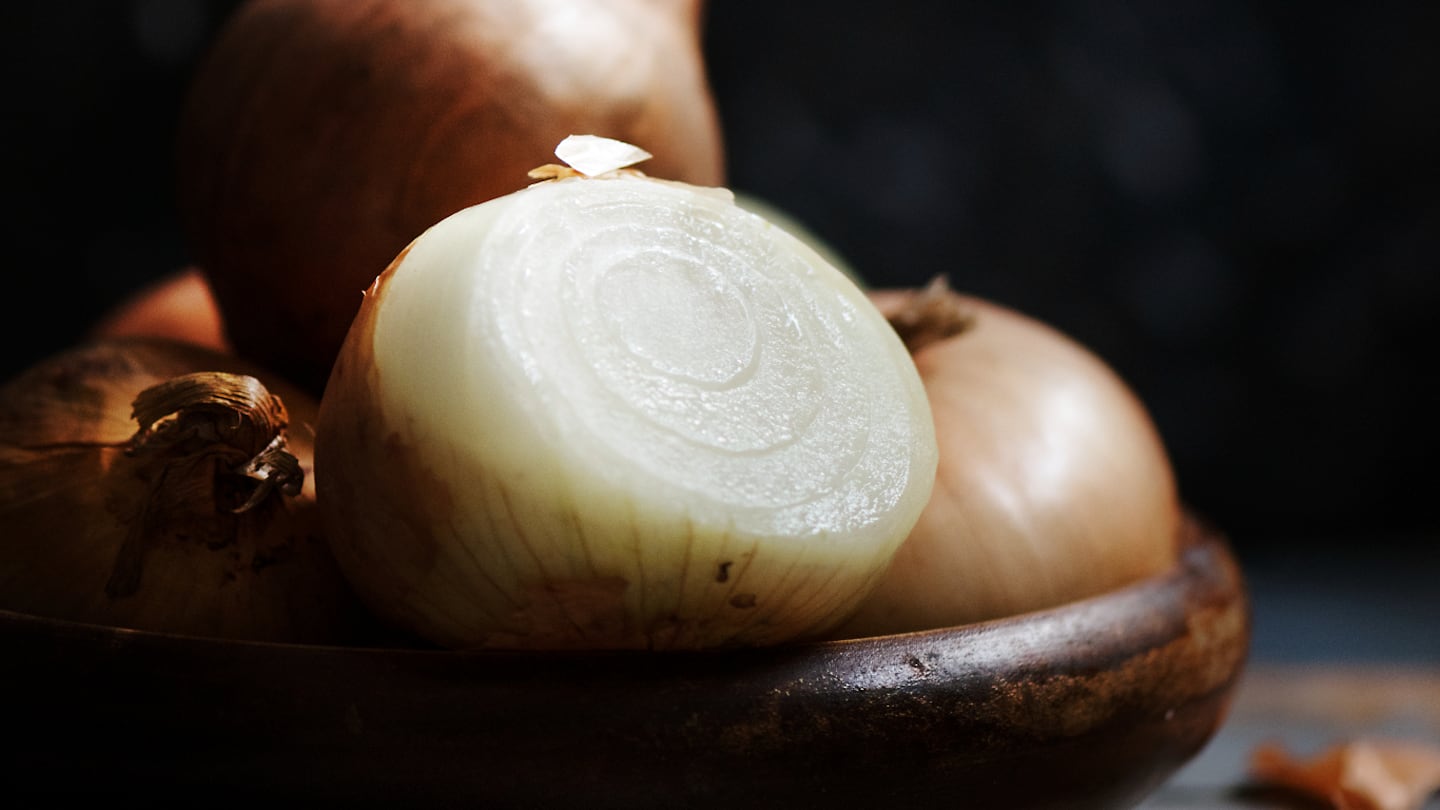 Cebolla cortada en rodajas sobre un plato de madera