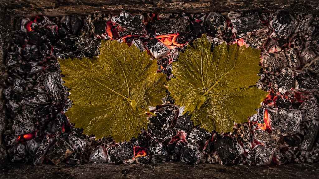 Asado argentino con hojas de parra sobre las brasas