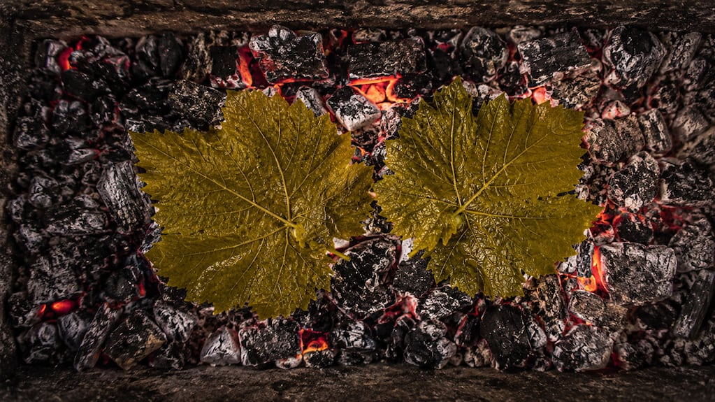 Asado argentino con hojas de parra sobre las brasas