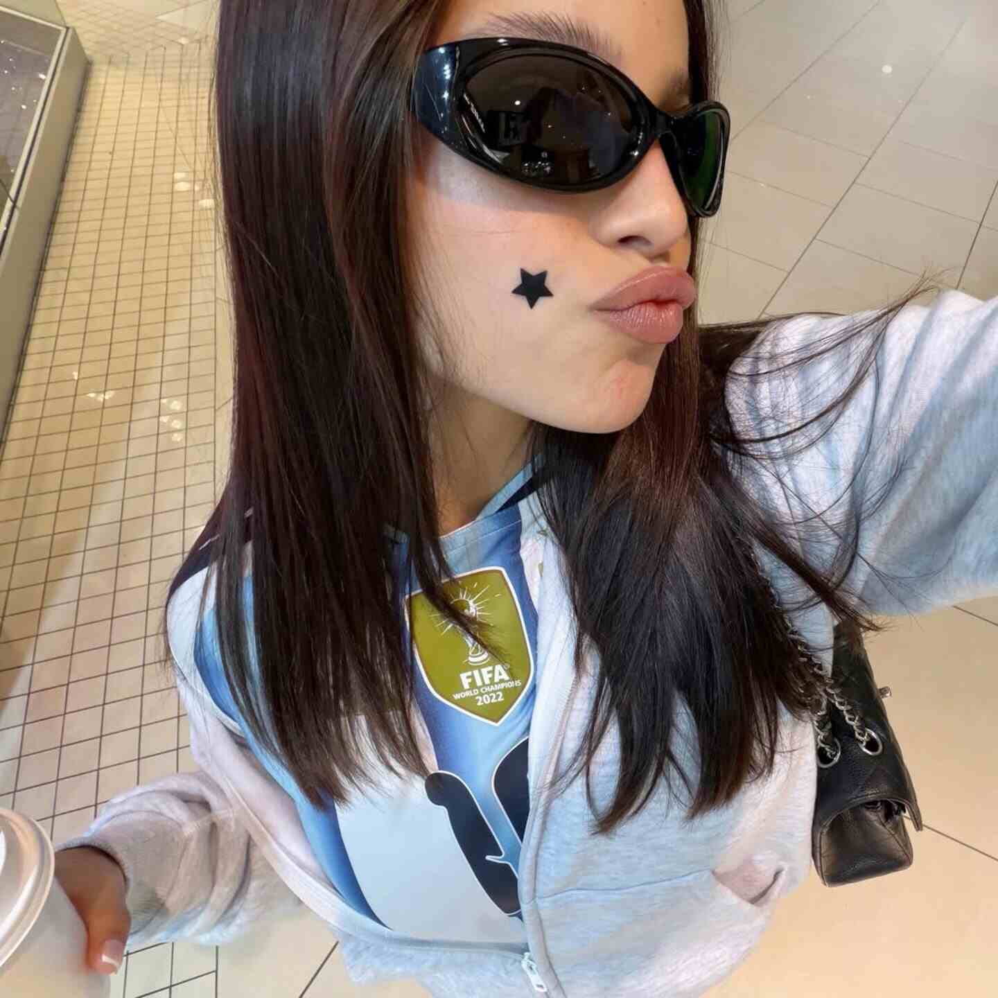 Emilia Mernes posando con gafas de sol y una estrella en la mejilla