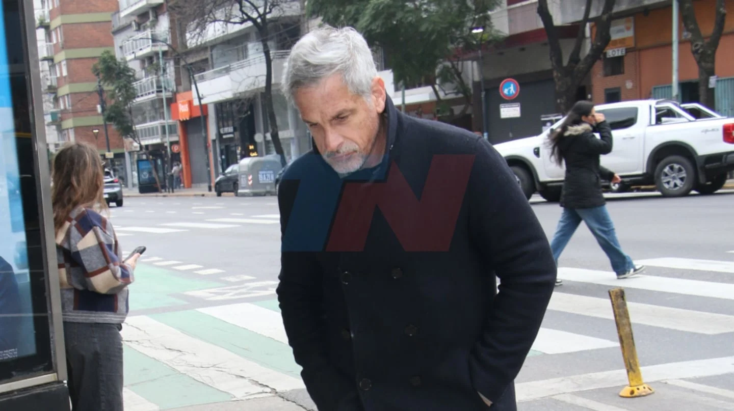 Hombre con abrigo oscuro camina cabizbajo por la calle en Chacarita