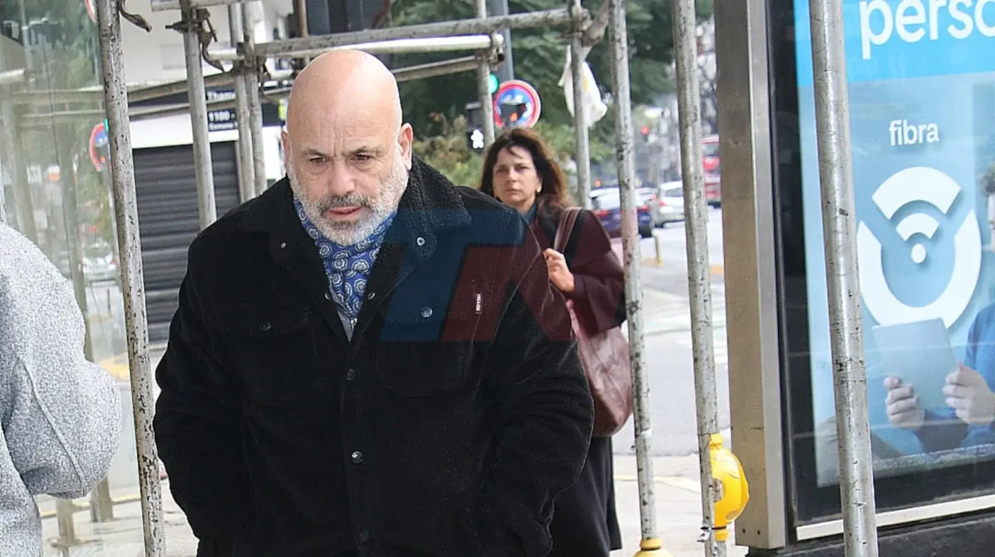 Hombre con abrigo oscuro caminando por la calle, con expresión seria