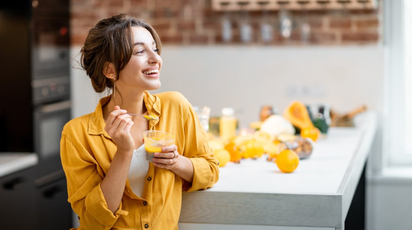 Mujer sonriente sosteniendo un postre de fruta en la cocina