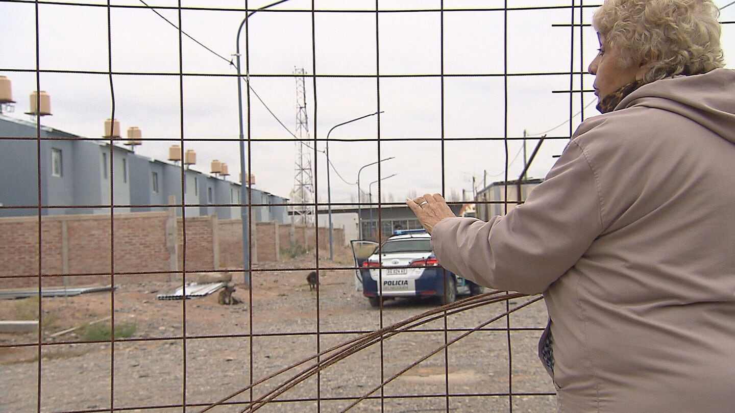 Mujer observa a través de una reja un barrio de viviendas en Neuquén