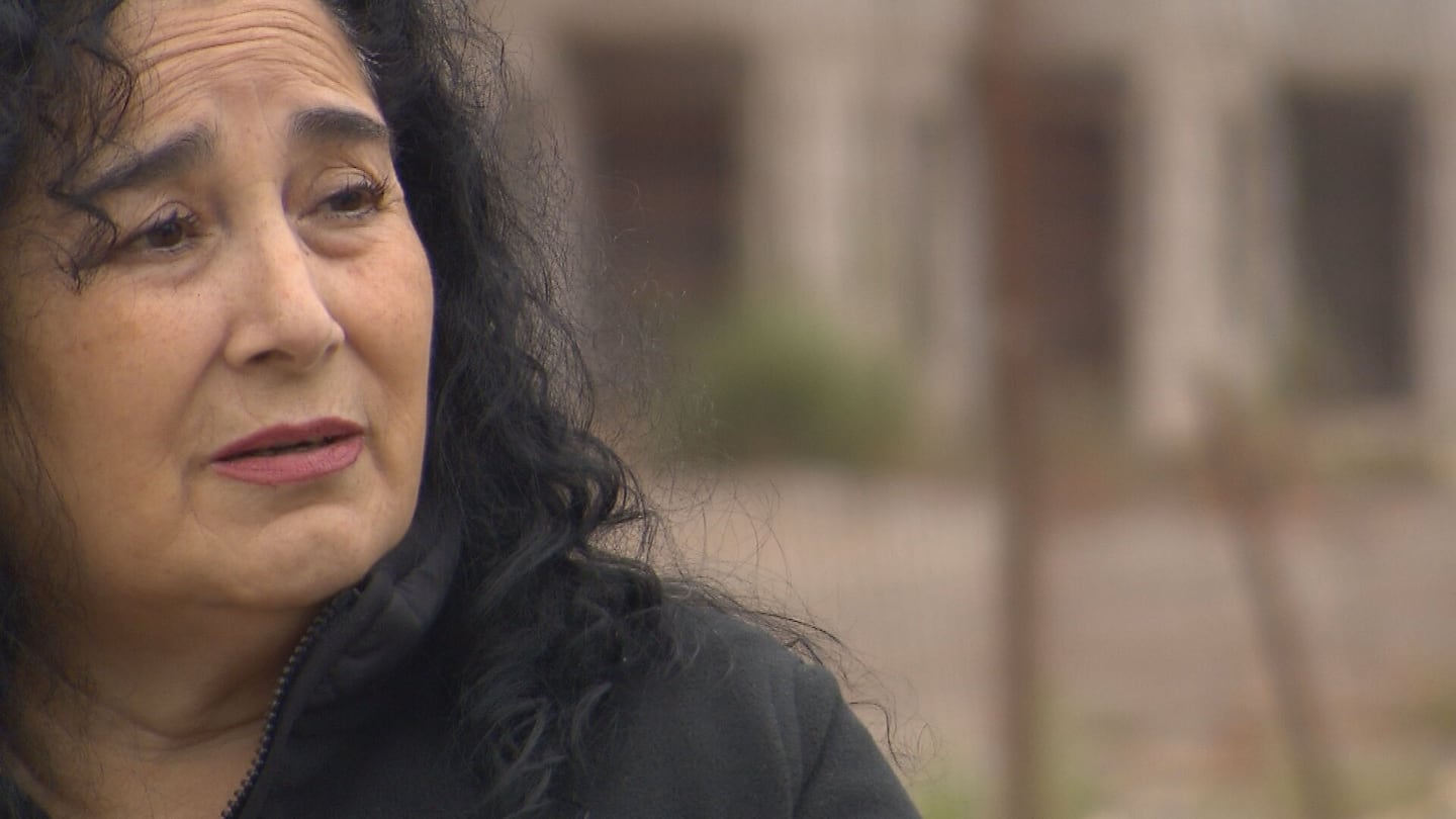 Mujer con cabello rizado y oscuro, expresando preocupación en un entorno de construcción abandonada