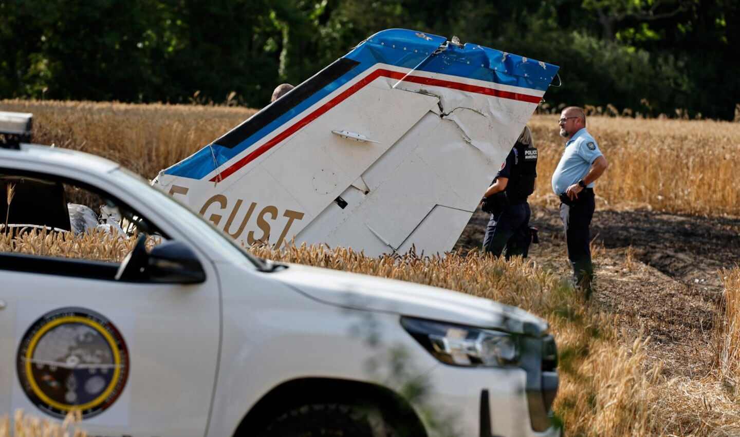 Restos de un avión accidentado en un campo con autoridades presentes
