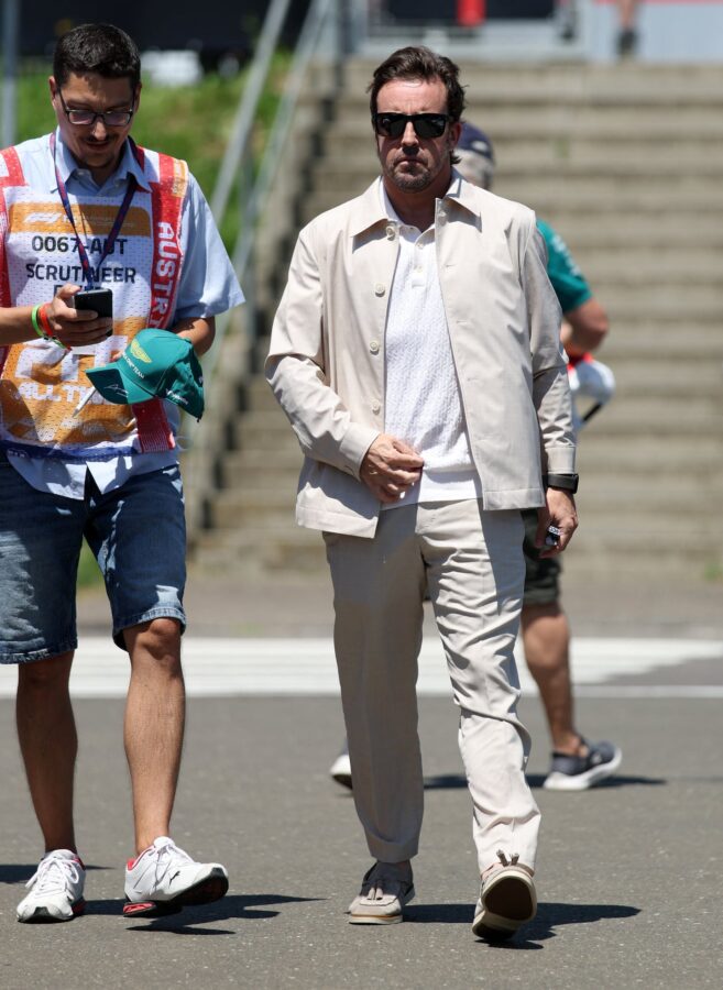 Fernando Alonso caminando en el Gran Premio de Austria, vestido con un traje claro