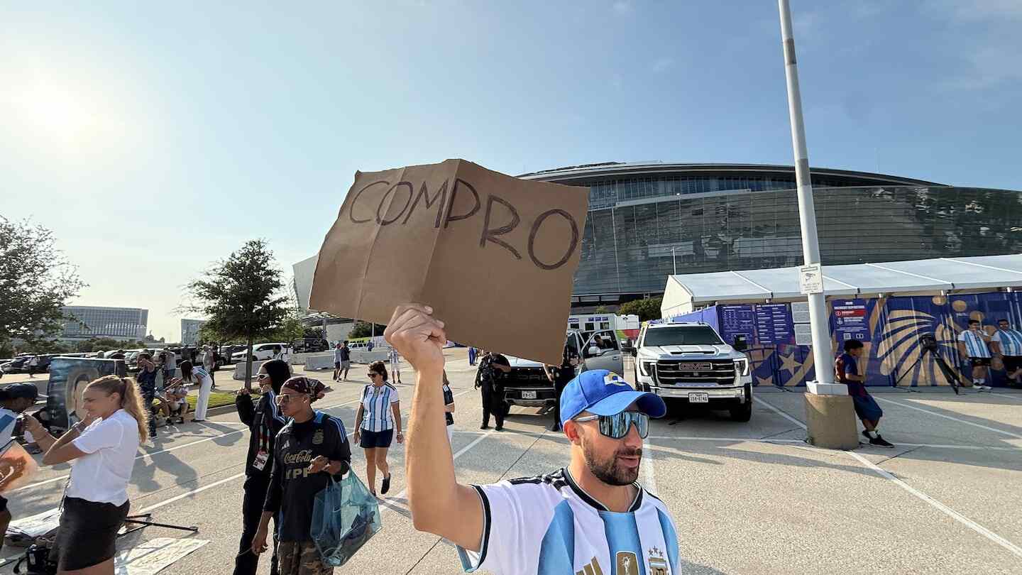Hombre con cartel que dice 'COMPRO' en el exterior del estadio en Dallas antes del partido Argentina-Austria