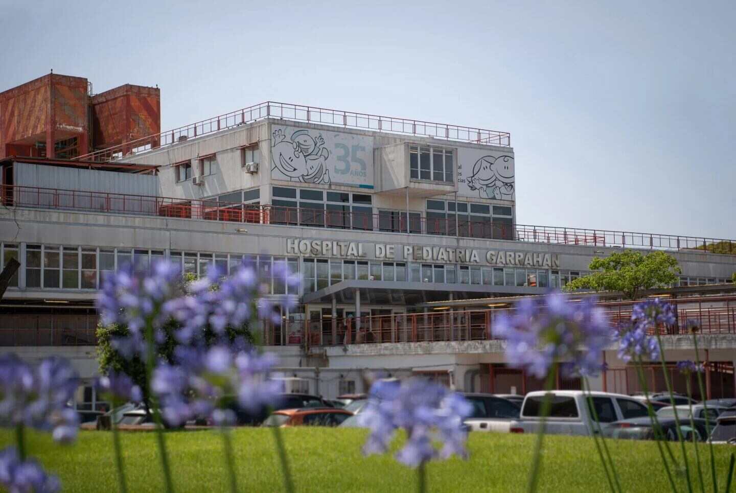 Fachada del Hospital de Pediatría Garrahan con flores en primer plano