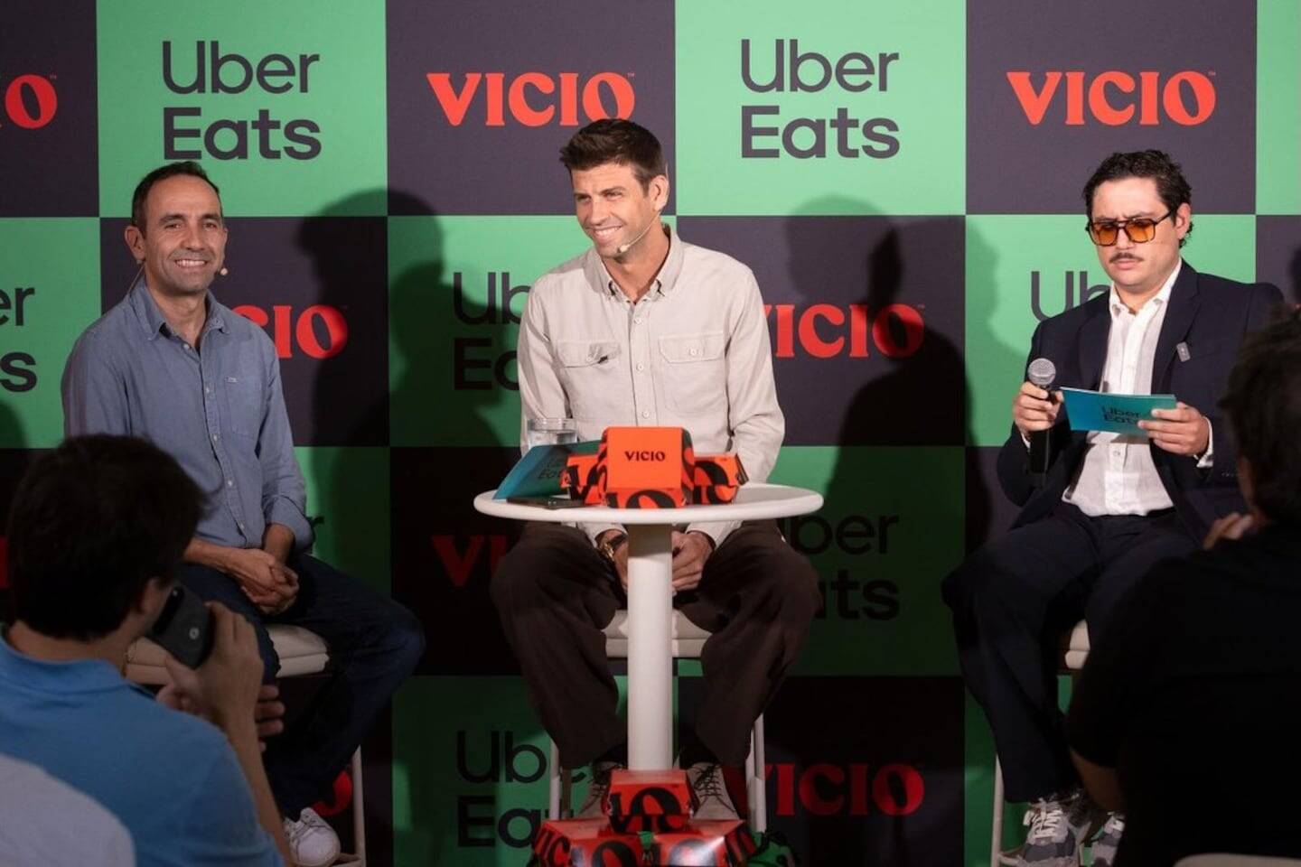 Gerard Piqué sonriente en un evento promocional con dos presentadores