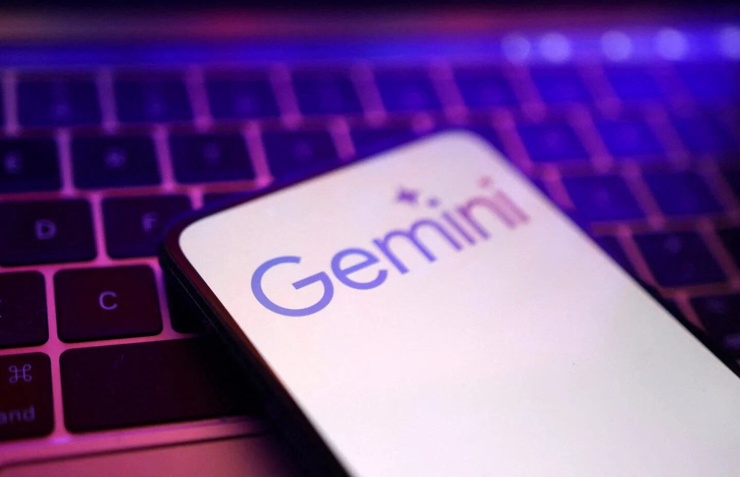 Pantalla de un teléfono móvil con el logo de Google Gemini sobre un teclado iluminado