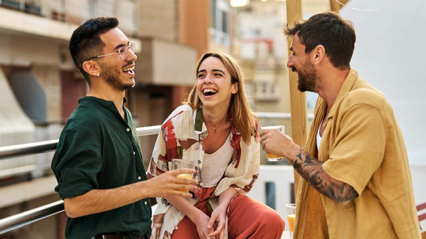 Tres amigos riendo y disfrutando de una conversación en una terraza