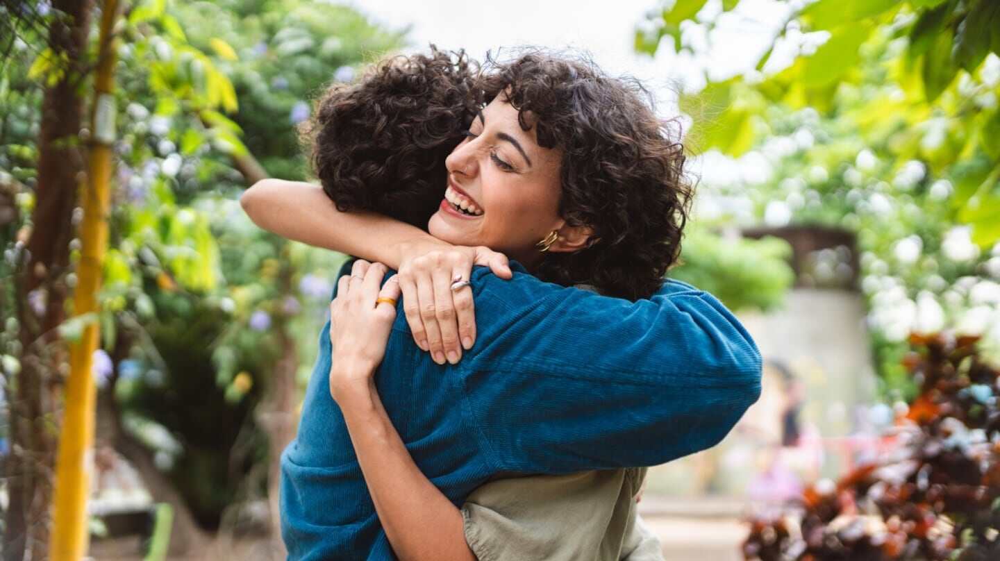 Pareja de amigos abrazándose con sonrisas en un entorno natural