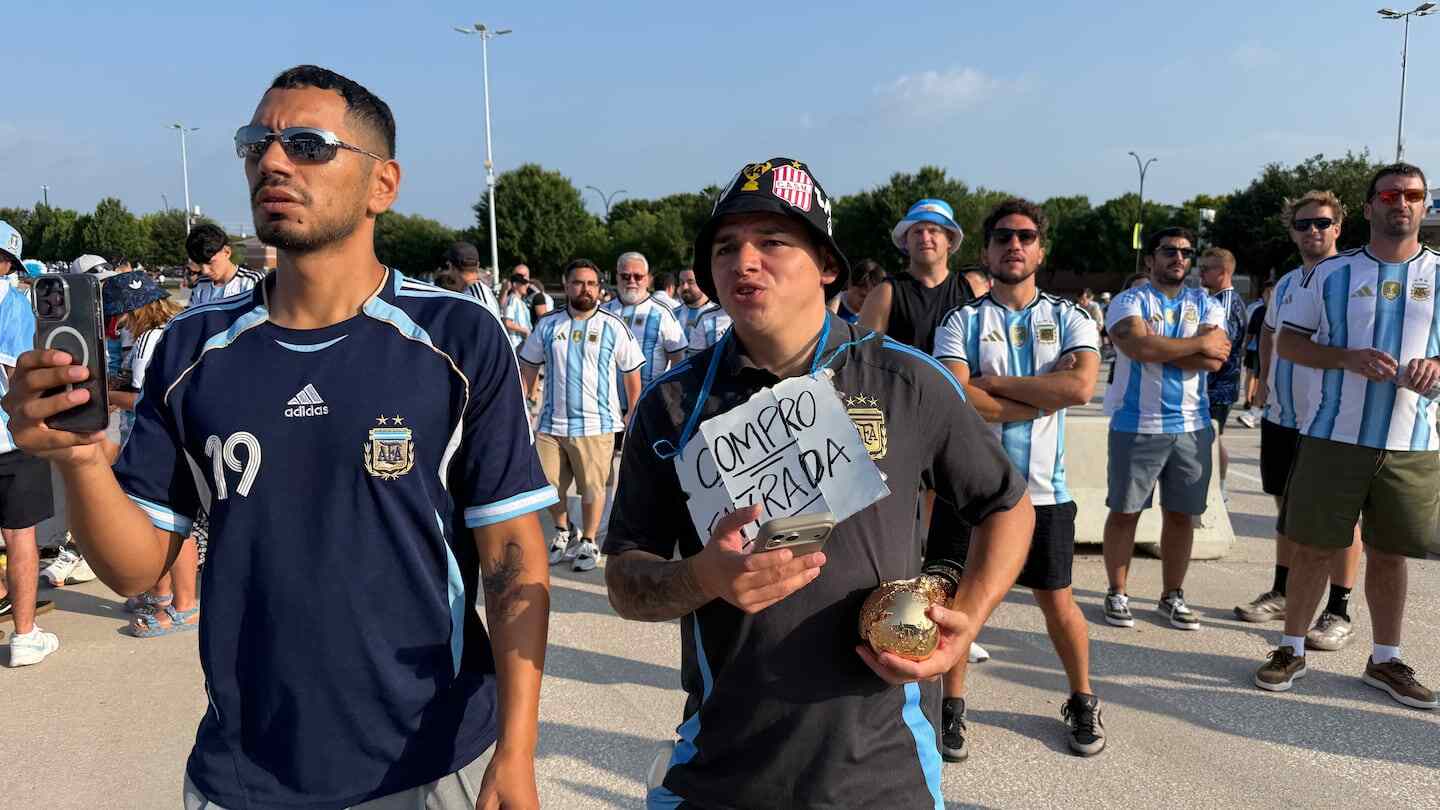 Hinchas argentinos en la entrada del estadio sosteniendo un cartel que dice 'Compro entrada'