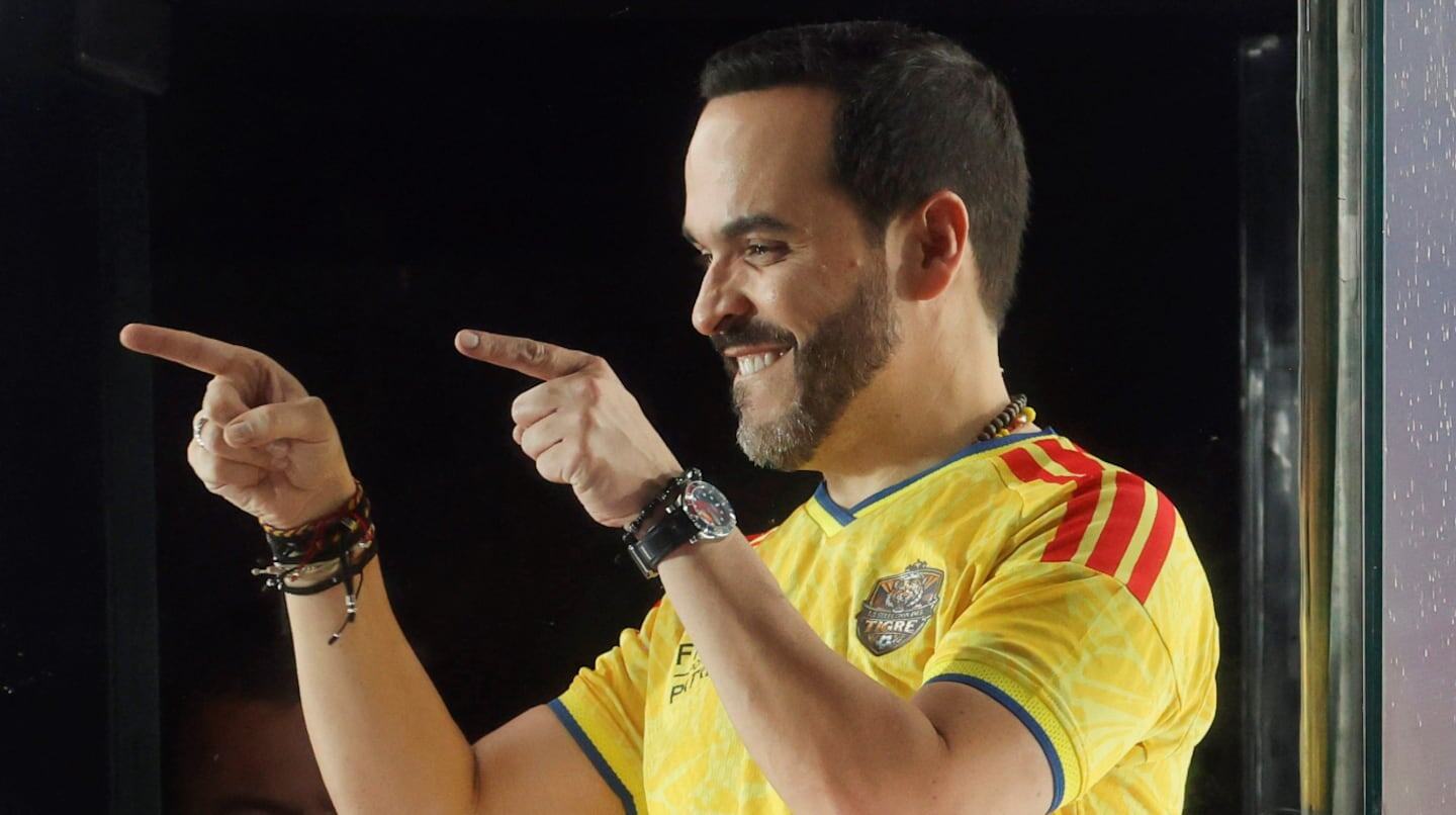 Iván Cepeda sonríe y señala mientras viste una camiseta amarilla en un evento público