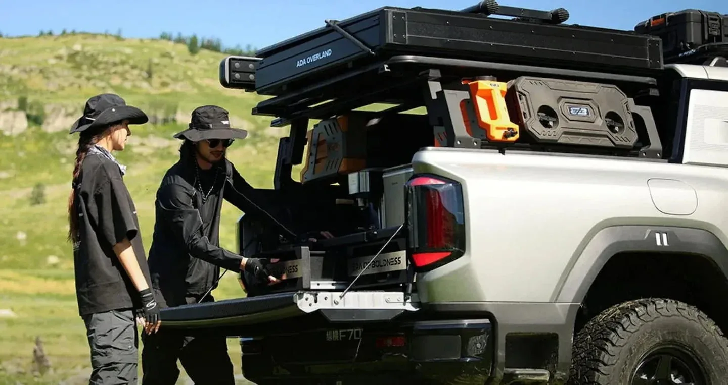 Dos personas interactuando con la parte trasera de una pick up híbrida Jetour Zongheng F700 en un entorno natural