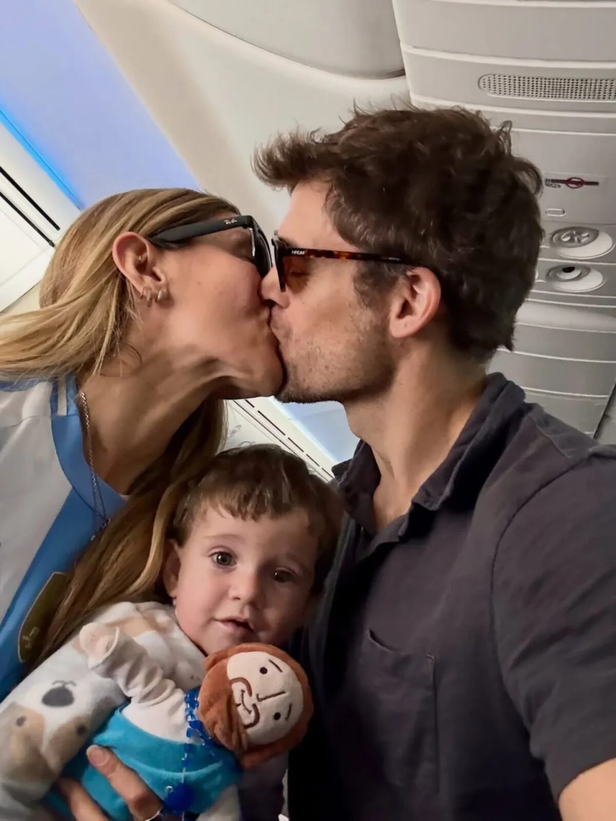 Jimena Barón besa a su pareja mientras sostiene a su hijo en brazos en un avión