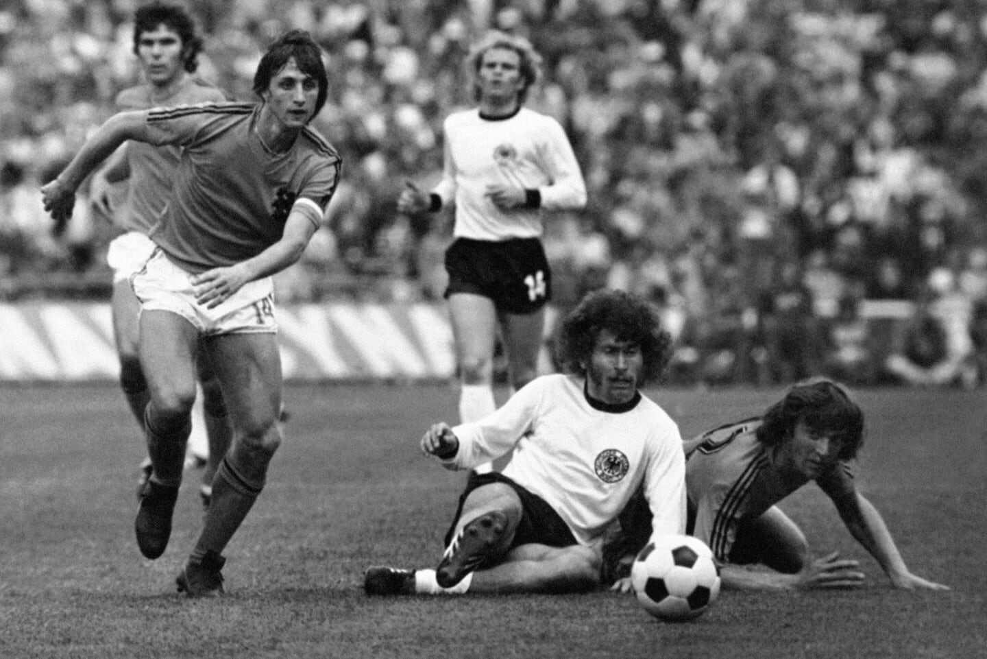 Jugadores de fútbol en un partido histórico del Mundial, con un jugador francés corriendo y dos alemanes en el suelo