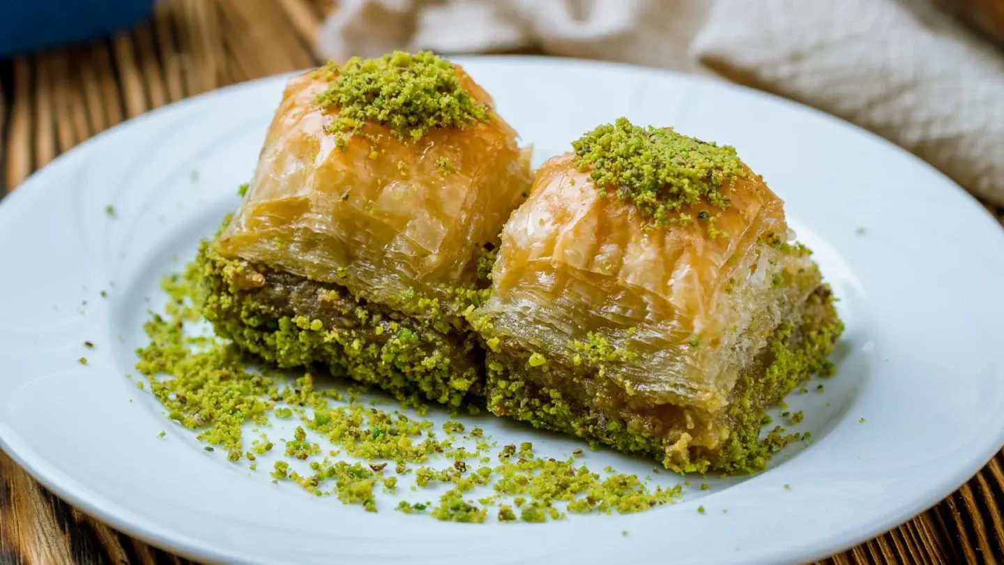 Dos piezas de baklava con pistacho sobre un plato blanco
