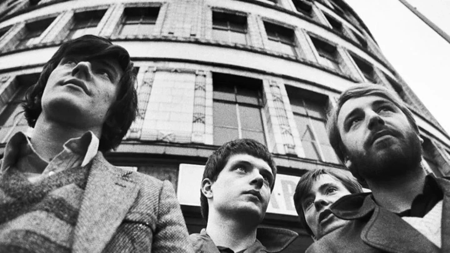 Cuatro miembros de Joy Division posando frente a un edificio en blanco y negro