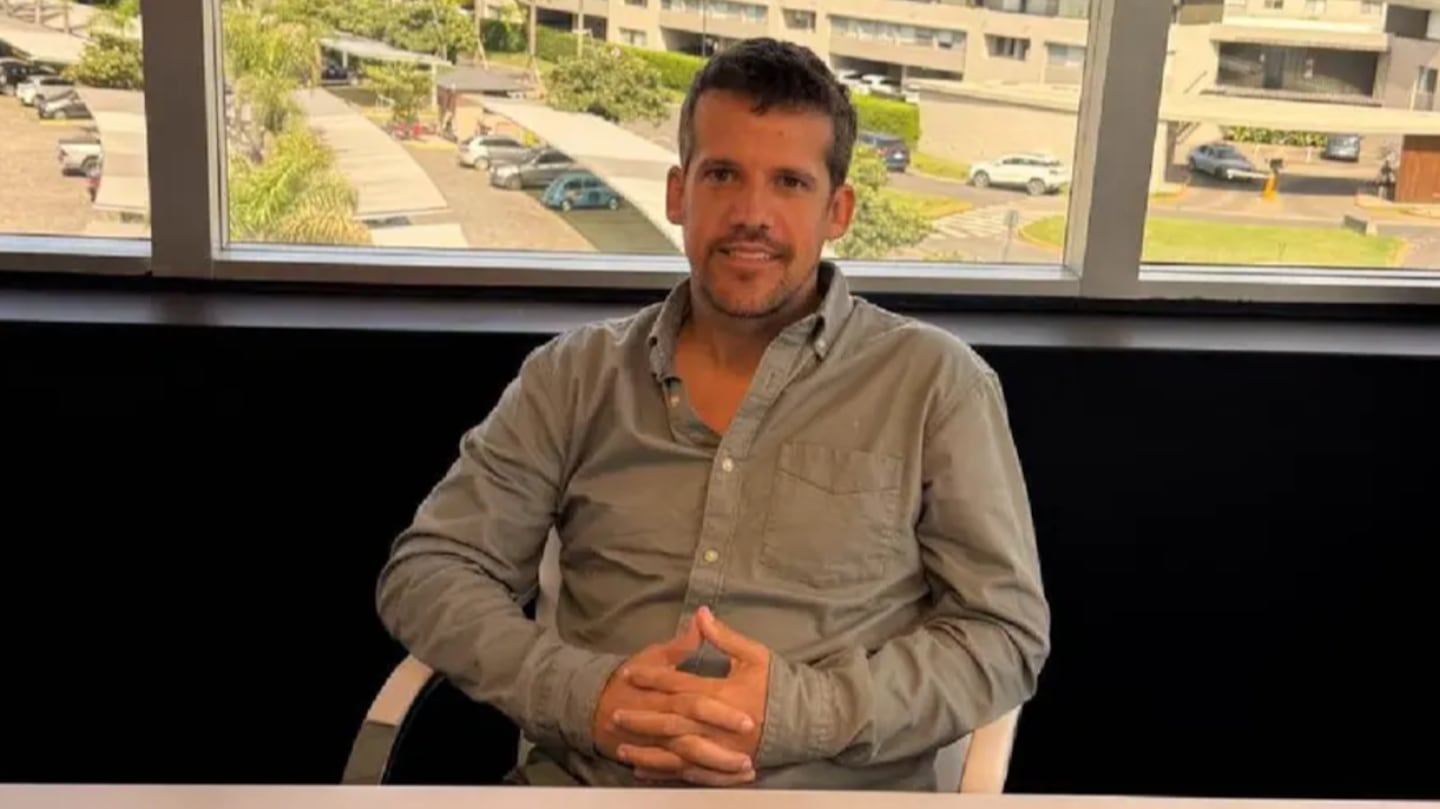 Juan Campos sentado en una oficina, sonriendo mientras se prepara para hablar sobre su app financiera Aikestar