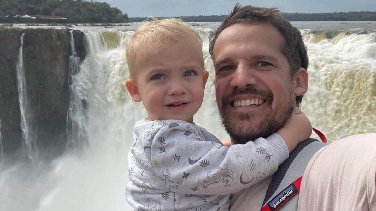 Juan Campos sosteniendo a un niño pequeño frente a las Cataratas del Iguazú