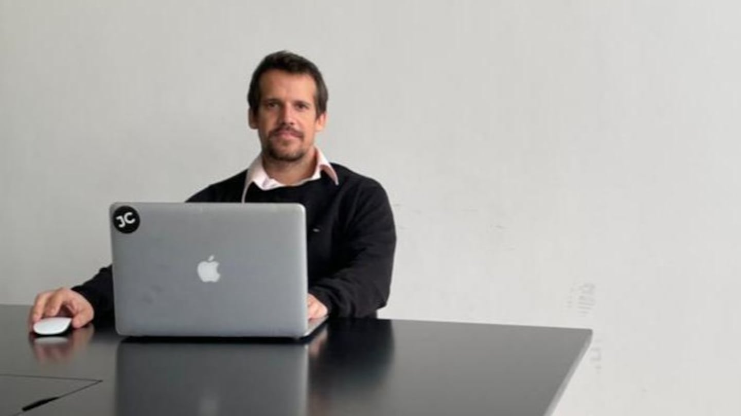 Juan Campos sentado frente a una computadora portátil en un entorno minimalista