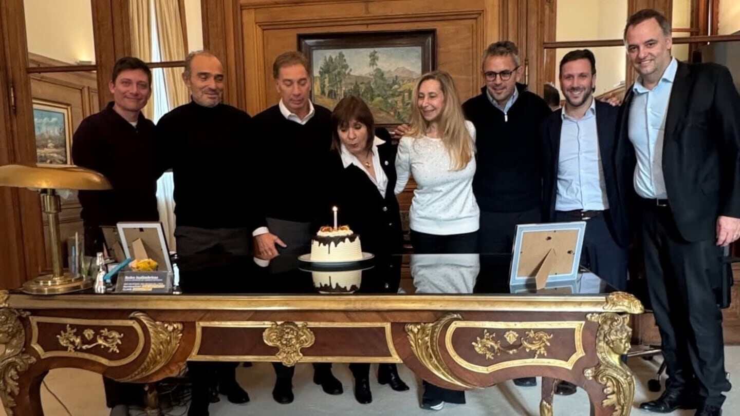 Grupo de personas en la Casa Rosada celebrando un cumpleaños con un pastel