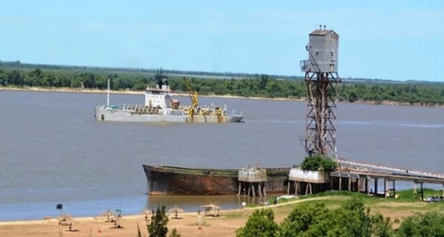 Barco navegando por la Vía Navegable Troncal con estructura portuaria en primer plano