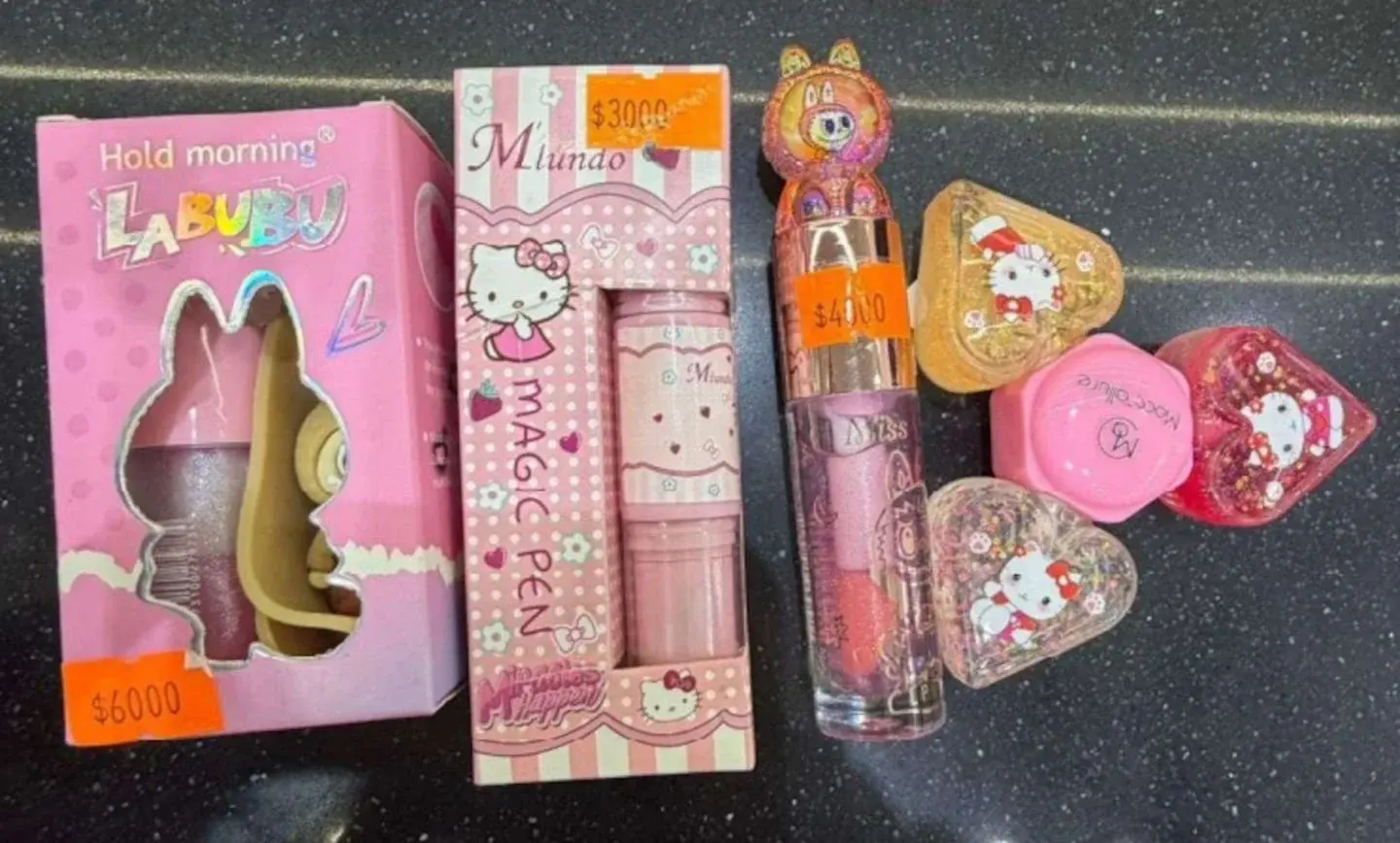 Cosméticos infantiles con imágenes de Hello Kitty y Labubu en una superficie oscura