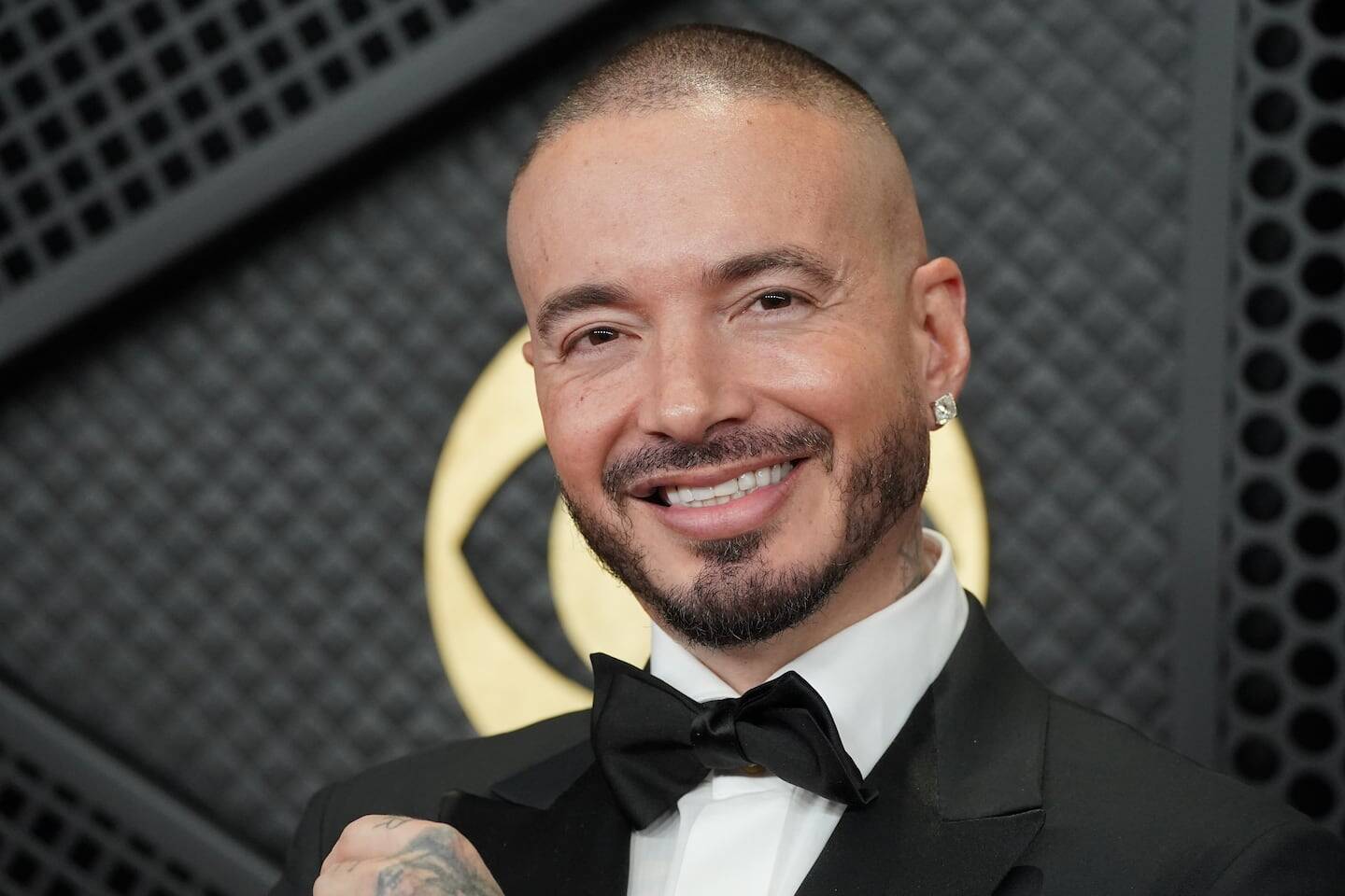 J Balvin sonriendo con un traje negro en un evento