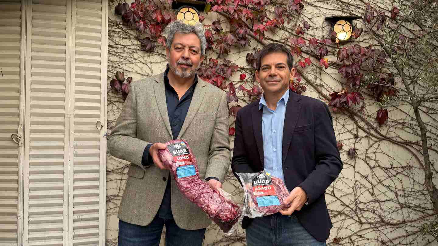 Dos hombres sosteniendo carne de búfalo en un entorno natural en Argentina