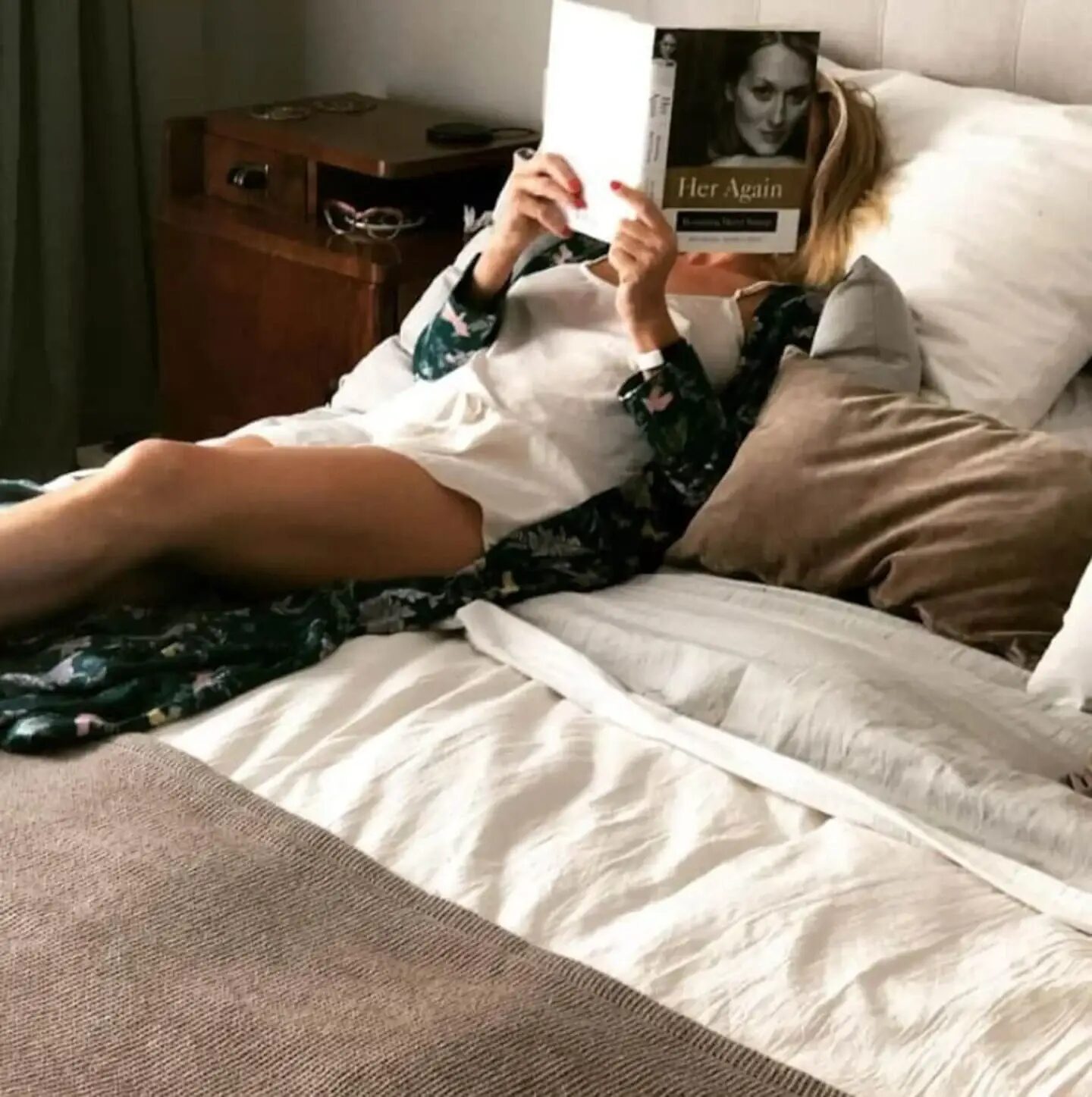 Mujer leyendo un libro en la cama con decoración vintage