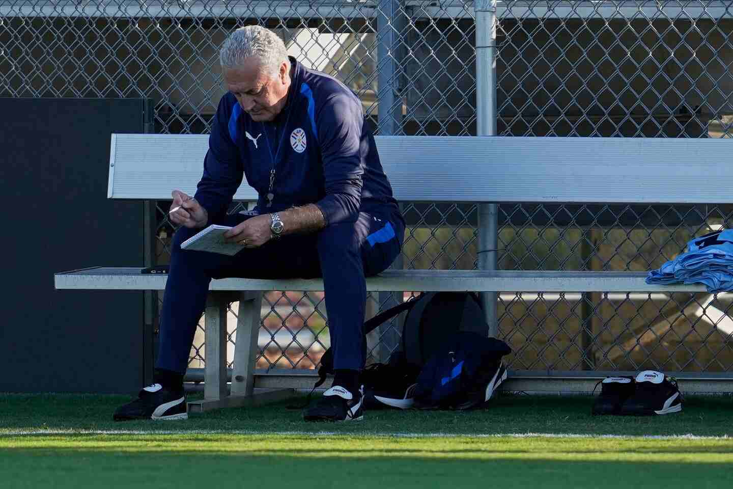 Gustavo Alfaro sentado en un banco, revisando notas antes del partido contra Turquía