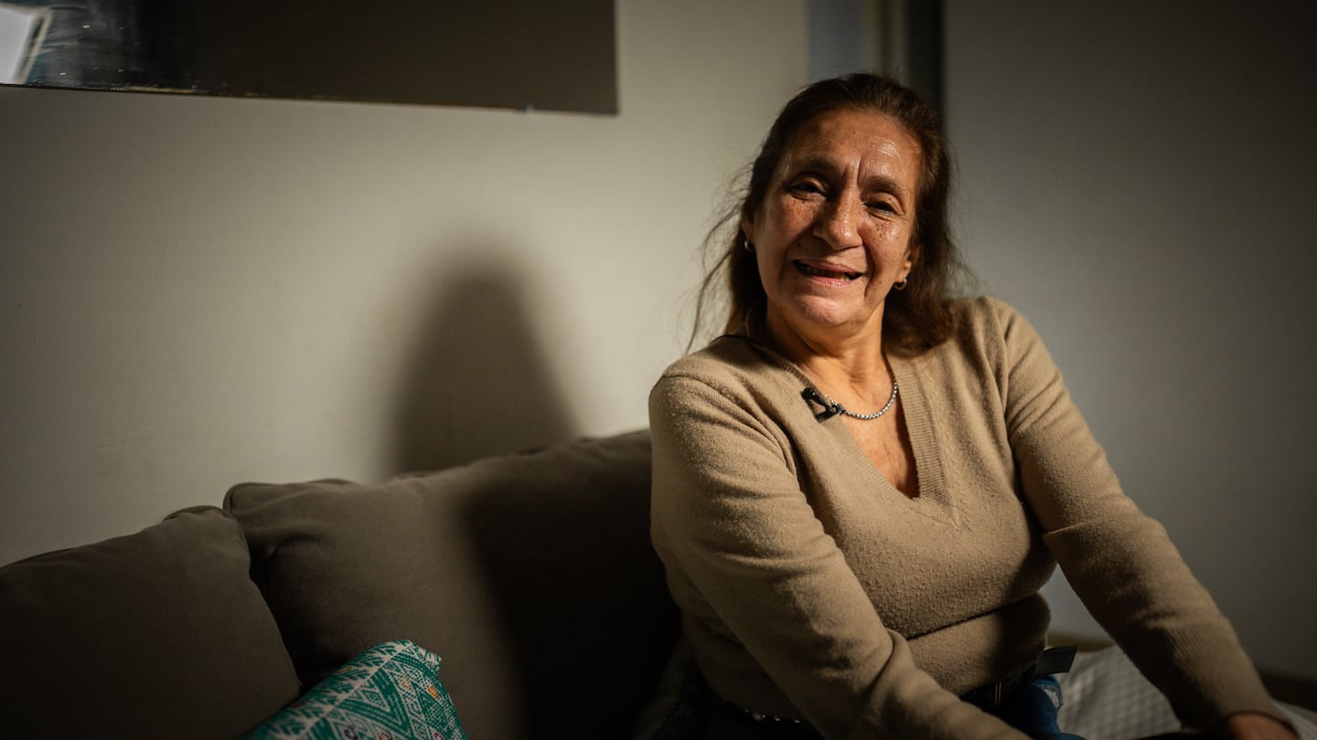 Mujer sonriente sentada en un sofá, en un ambiente acogedor